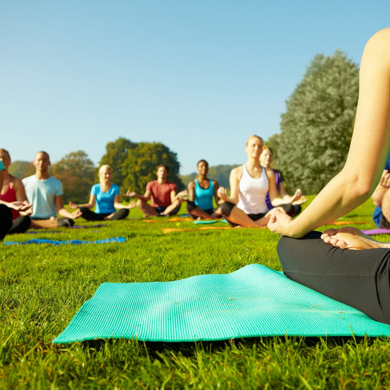 Group of people practicing yoga outdoors on a sunny day