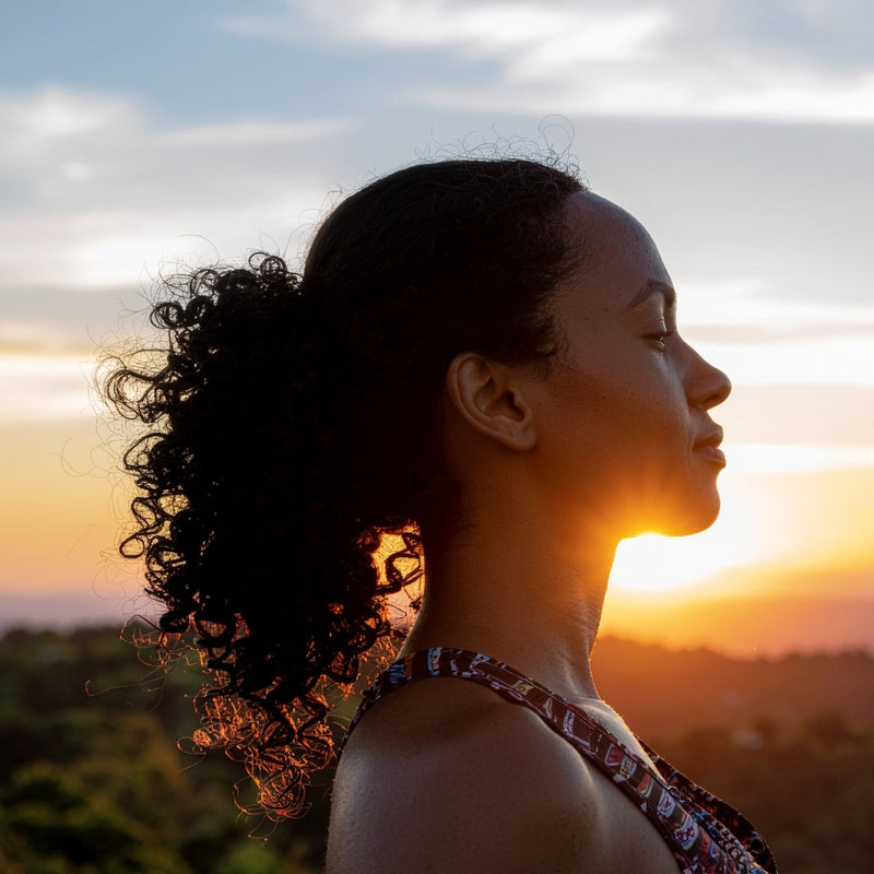 Woman with curly hair looking towards a sunset